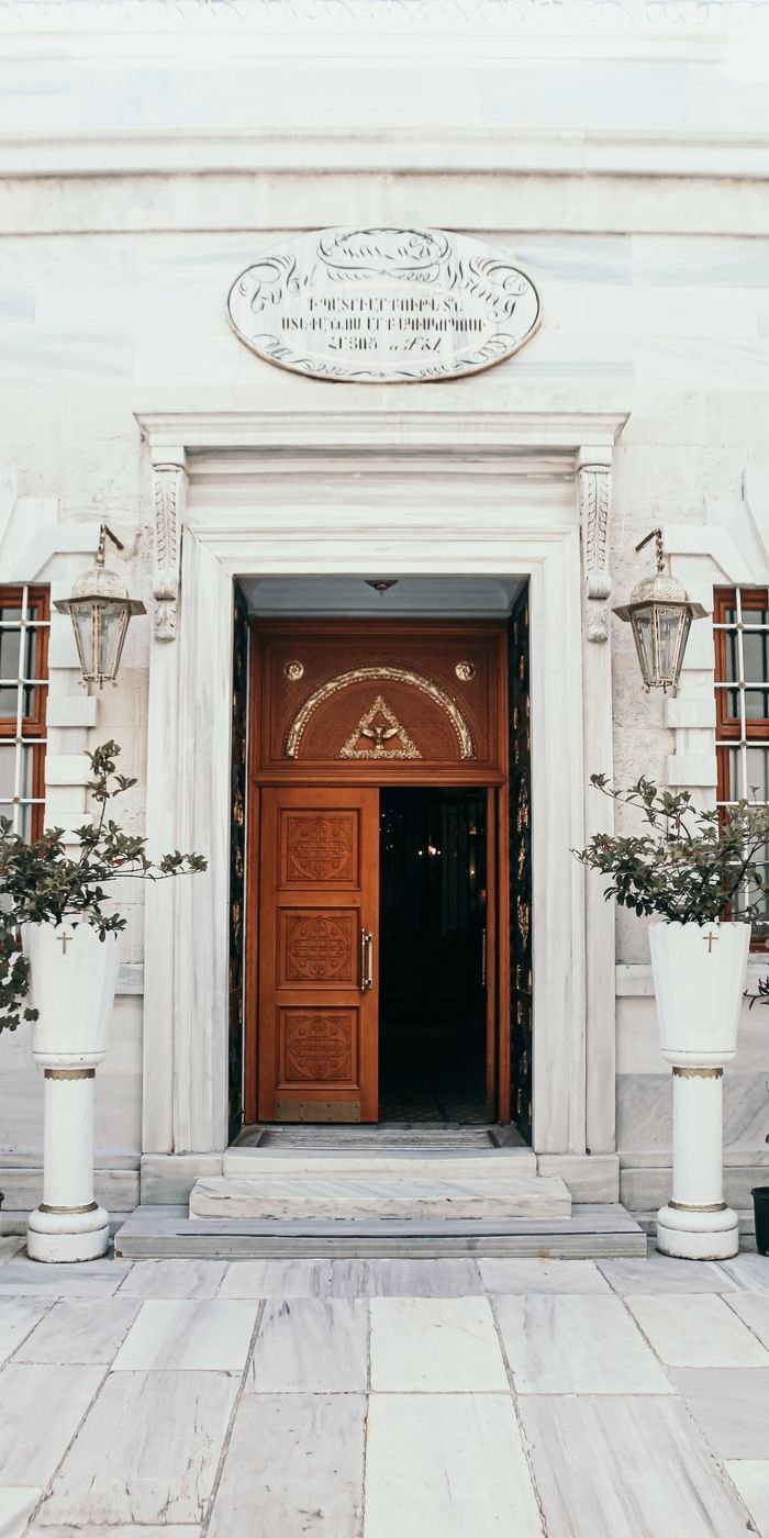 about-02 Beautiful architectural entrance featuring wooden doors, ornate carvings, and lush plants in Istanbul, Türkiye.