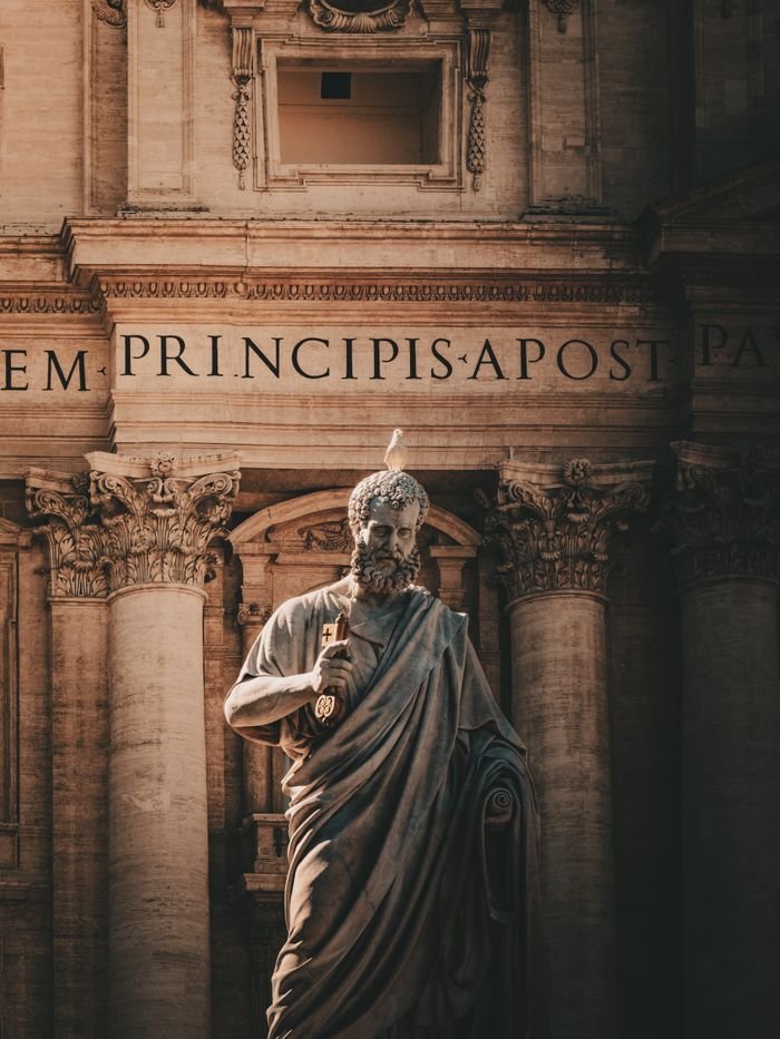 Statue of St. Peter in Vatican City with intricate architectural details behind.