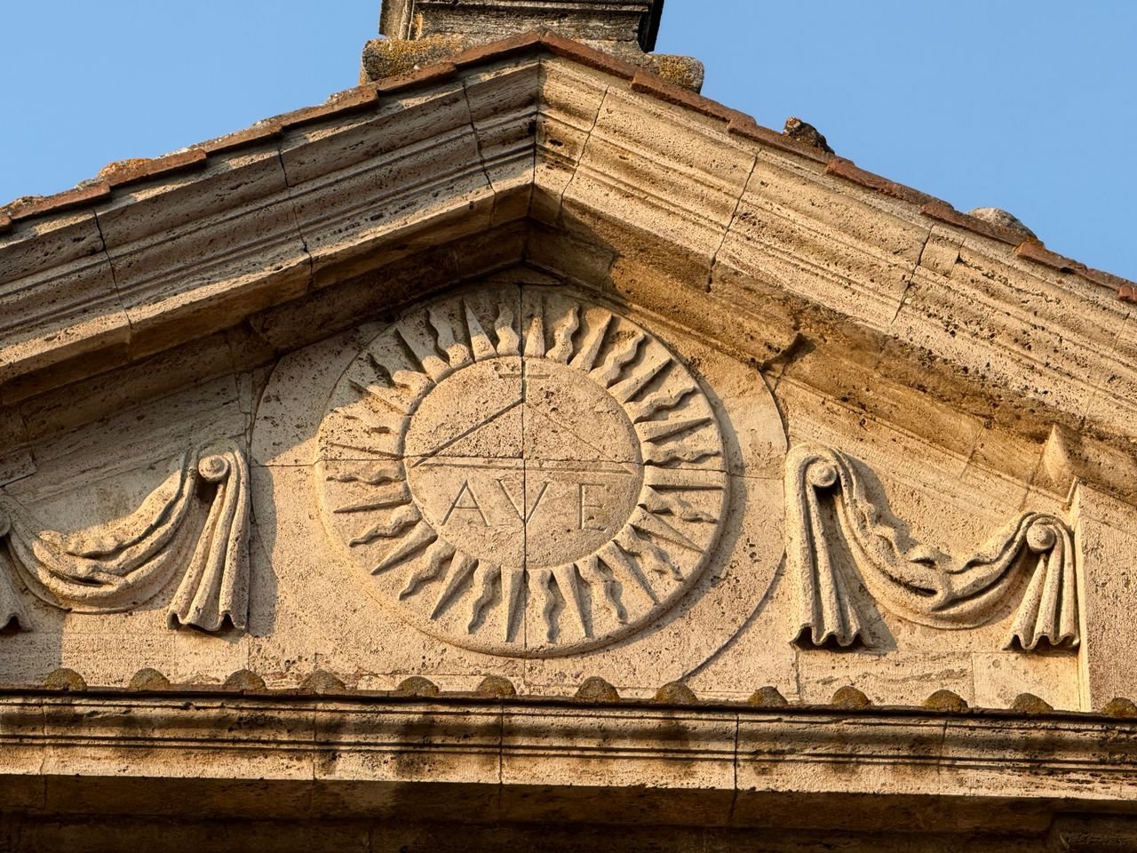 services-01 Detailed stone carving of architectural elements with Latin inscription in soft light.