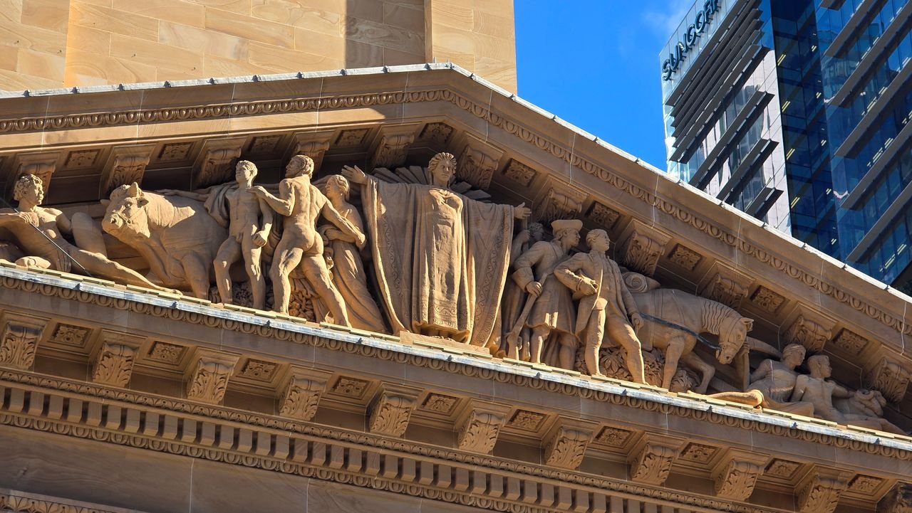 why-choose-us Close-up of detailed sculptures on a historical building facade under a clear blue sky.