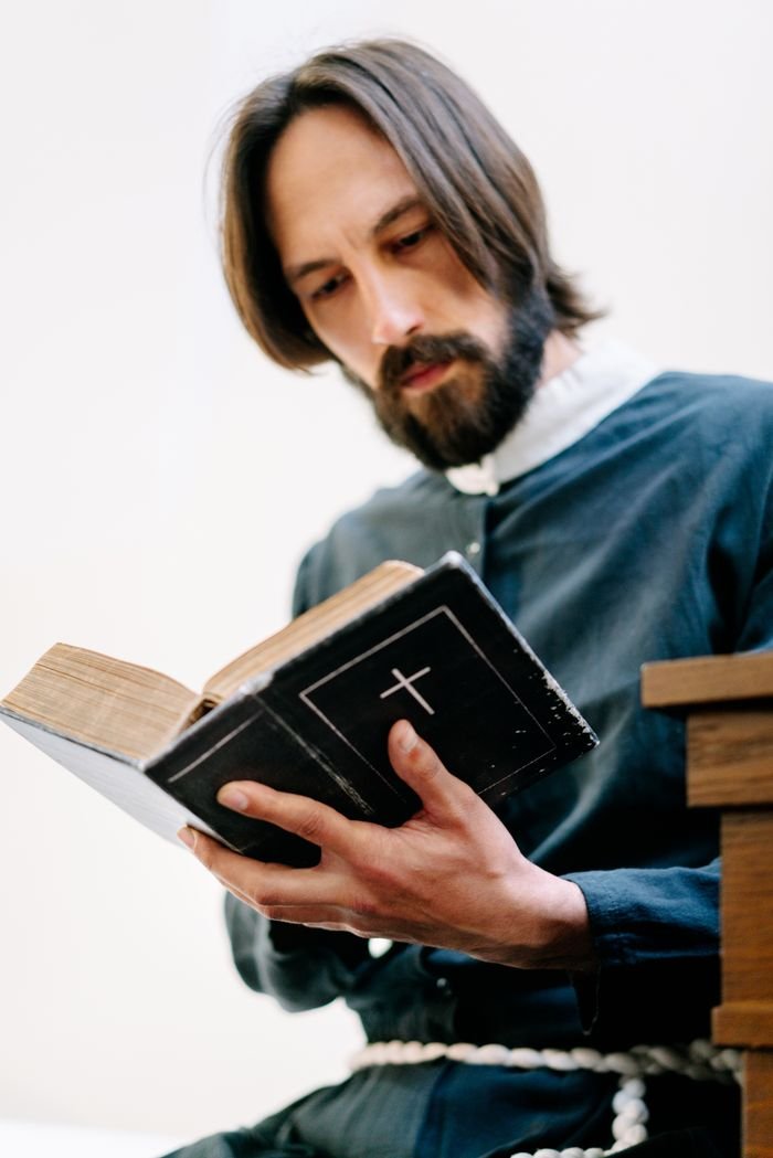services-01 Close-up of a bearded man reading a holy book with focus on facial expression.